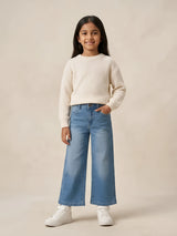 Young girl wearing stylish blue wide leg high waisted casual pants paired with a white sweater and sneakers