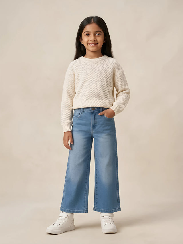Young girl wearing stylish blue wide leg high waisted casual pants paired with a white sweater and sneakers