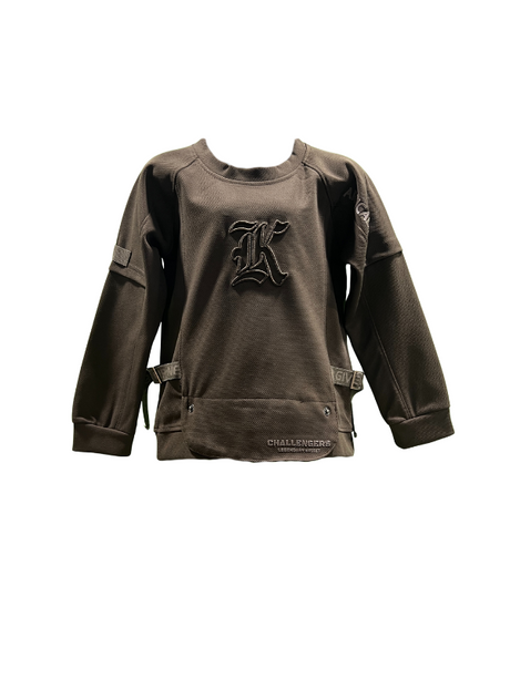 Camel brown/taupe boys' short-sleeve T-shirt with a subtle horizontal texture, featuring a small circular cross/flower emblem graphic on the chest in tan and white