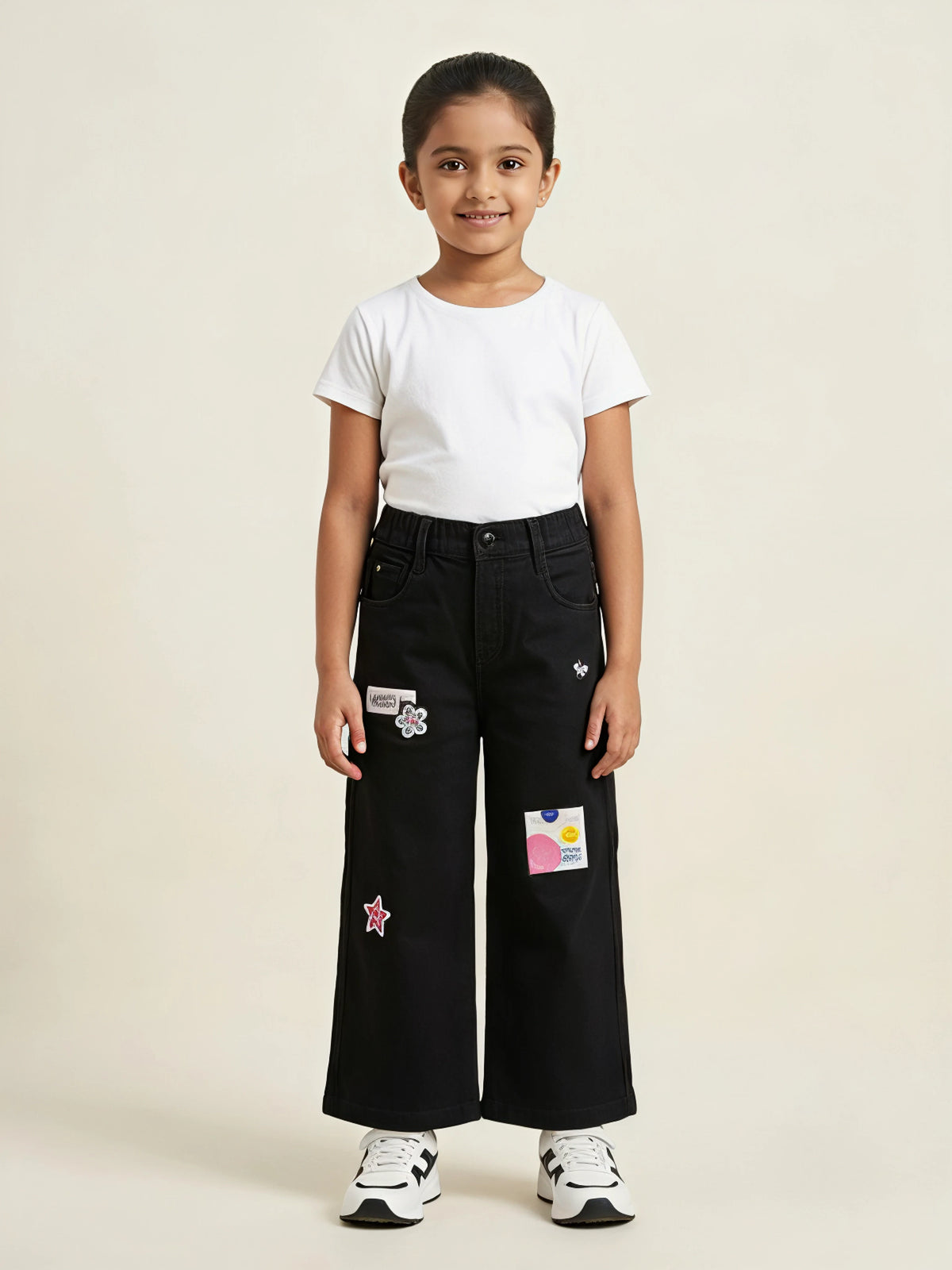 Young girl wearing black wide leg casual pants with graphic patches and front pockets
