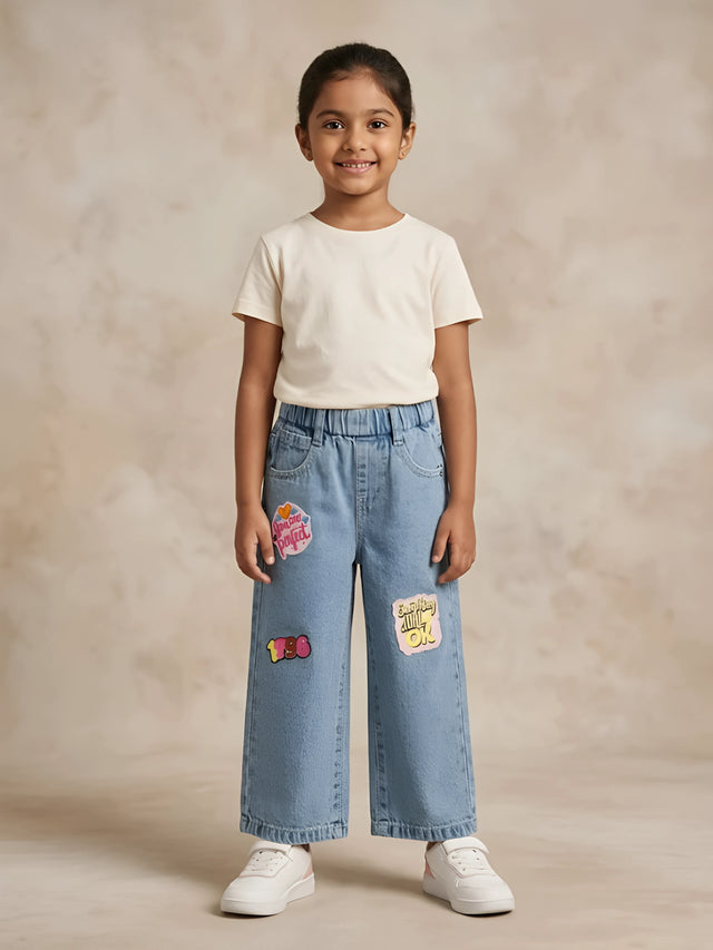 Young girl wearing light blue wide-leg casual pants with graphic patches and elastic waistband