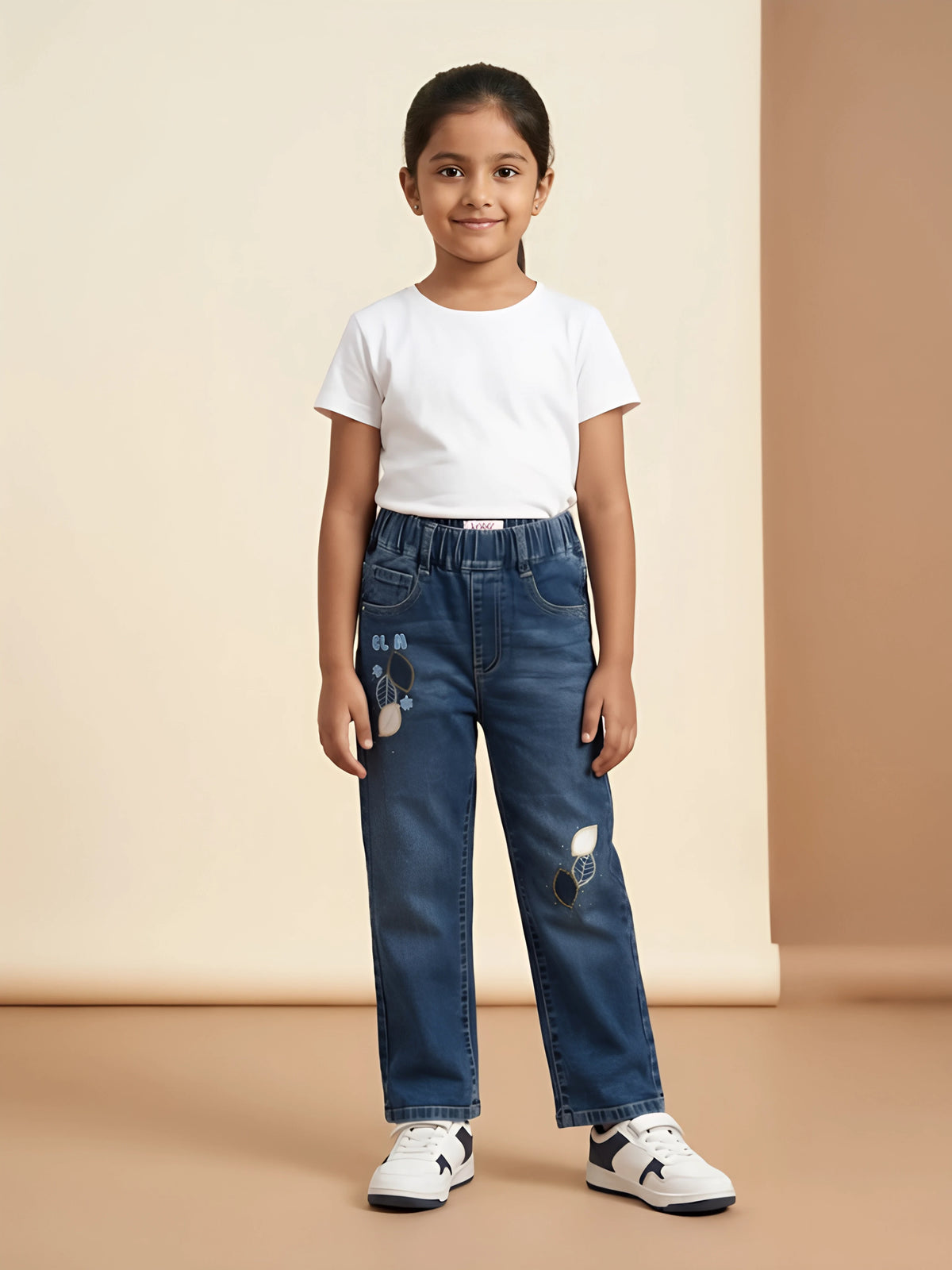 Young girl wearing blue embroidered casual pants with an elastic waist and a white t-shirt