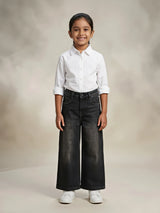 Young girl wearing stylish dark grey wide leg casual pants paired with a white button-down shirt and white sneakers.