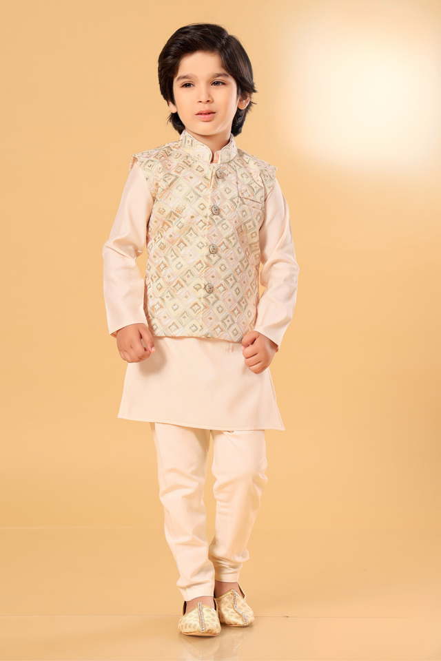  Young boy wearing a cream/off-white kurta pajama set, layered with a sleeveless matching embroidered Nehru jacket, featuring geometric or circular patterned work.