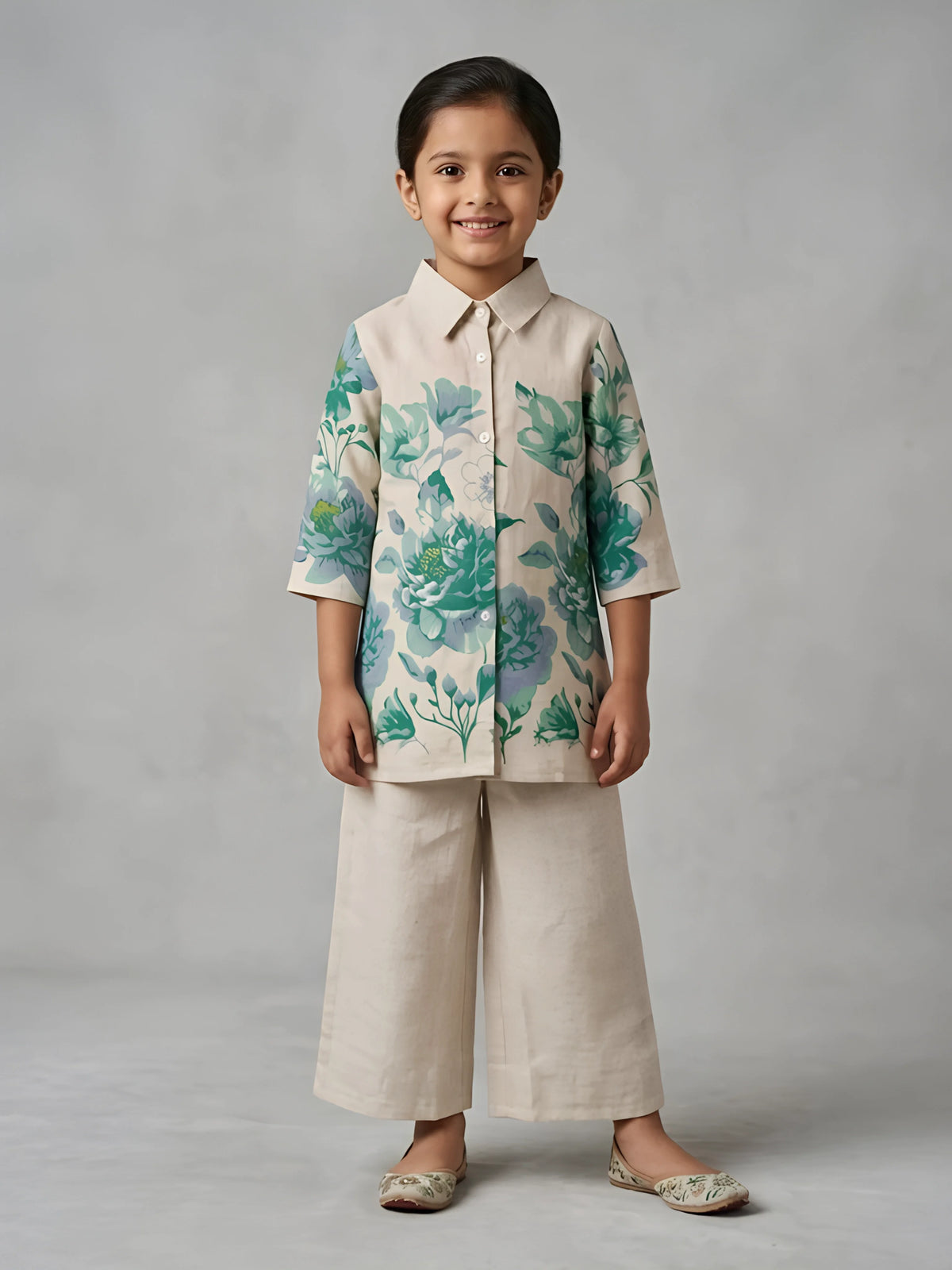 Young girl wearing a cream and blue floral printed button-down shirt top paired with matching relaxed wide-leg palazzo pants.