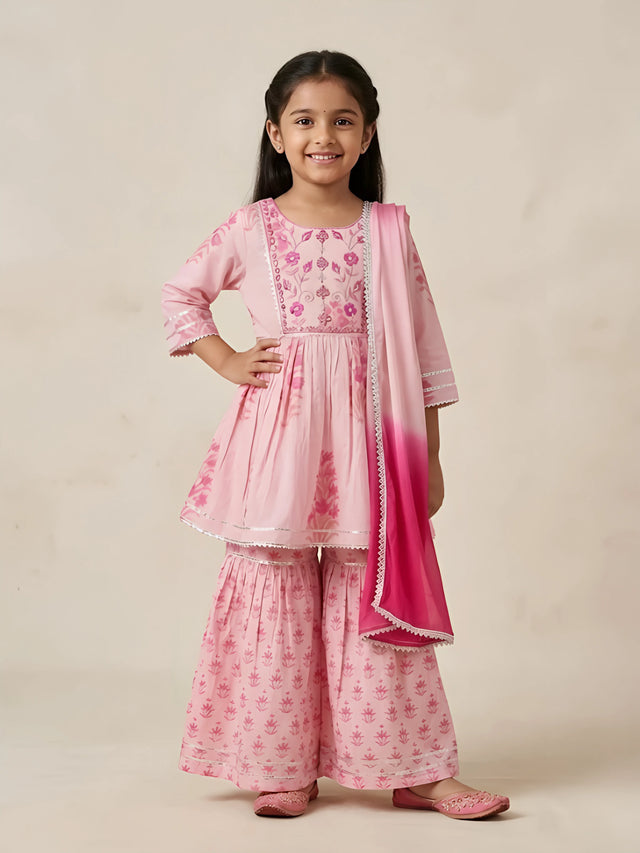Young girl wearing a light pink floral printed and embroidered sharara set with a dual-tone pink dupatta