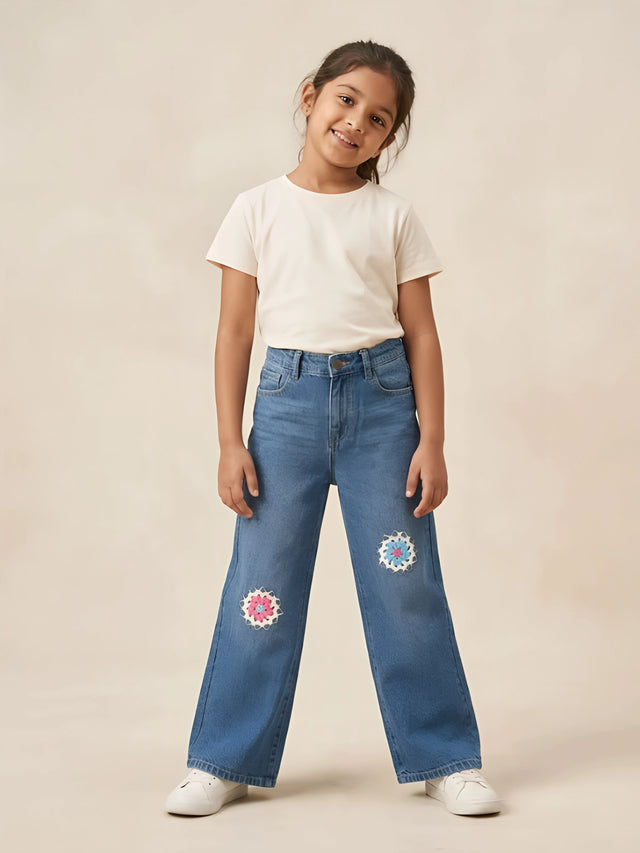 Young girl wearing light blue wide leg casual pants featuring floral crochet embroidery on knees