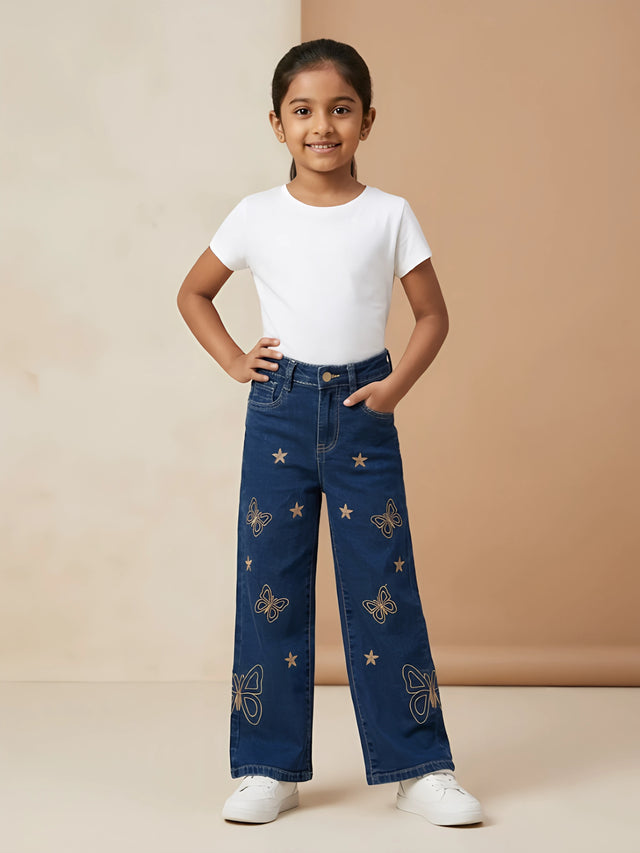 Young girl wearing navy blue wide-leg casual pants with star and butterfly embroidered motifs paired with a white t-shirt.