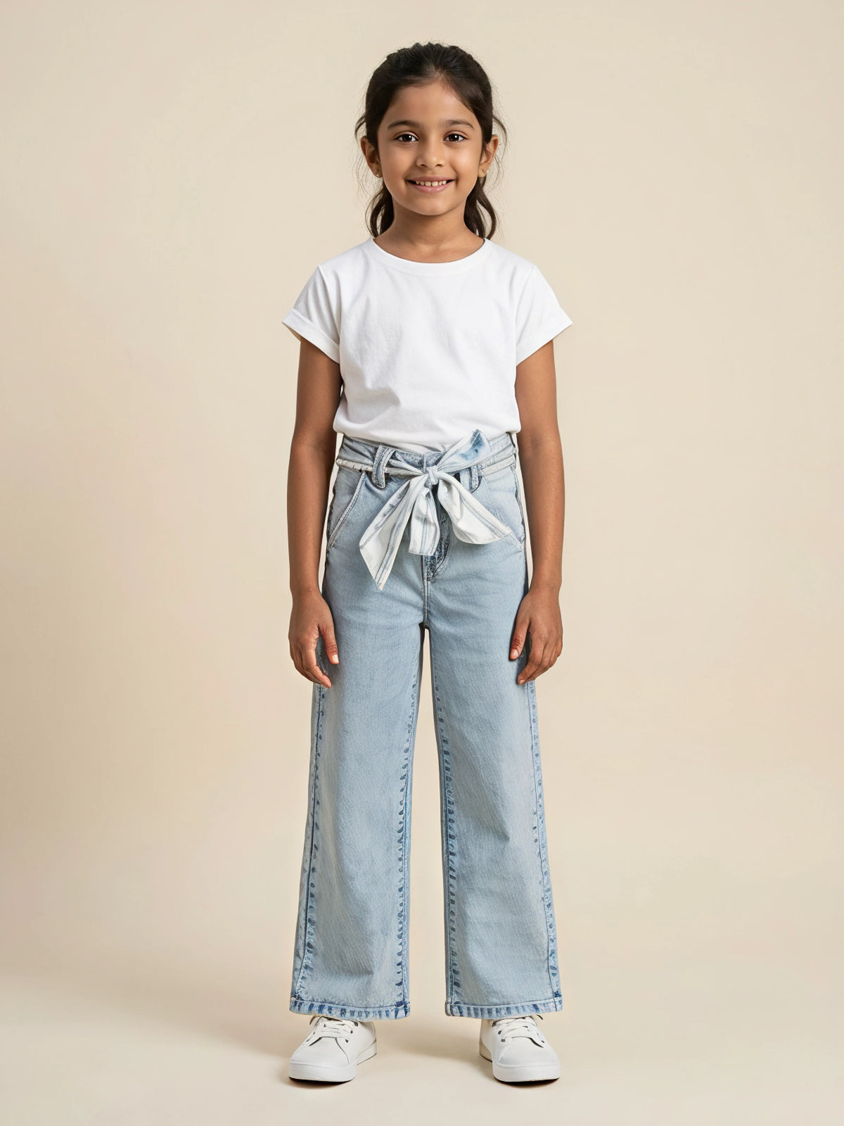 Young girl wearing light blue wide leg casual pants with waist belt tie-up and side pockets paired with a white t-shirt and sneakers