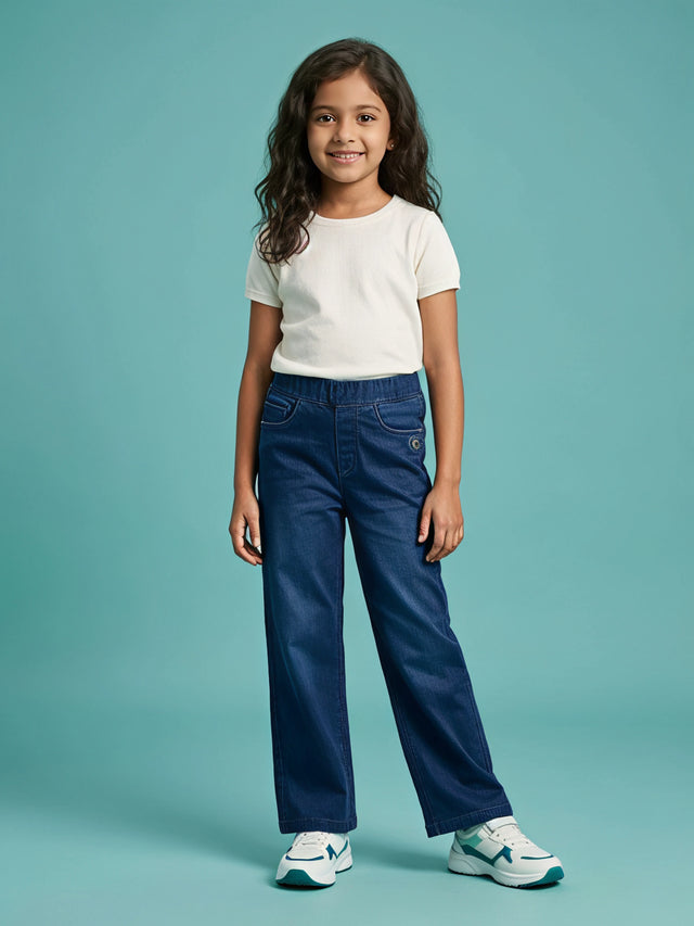 Young girl wearing stylish navy blue elastic waist casual pants paired with a plain white t-shirt and white sneakers.