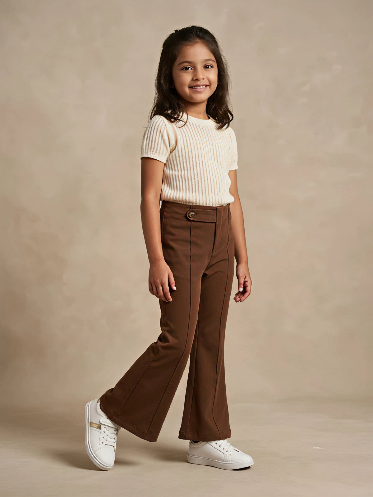 Young girl wearing brown high-waist flared casual pants with front seam detailing and white sneakers