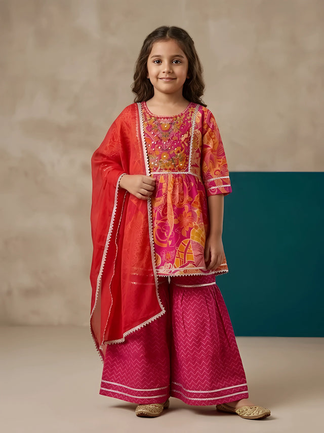 Young girl wearing a vibrant pink floral printed short kurta with matching flared geometric-pattern sharara pants and a red-pink dupatta