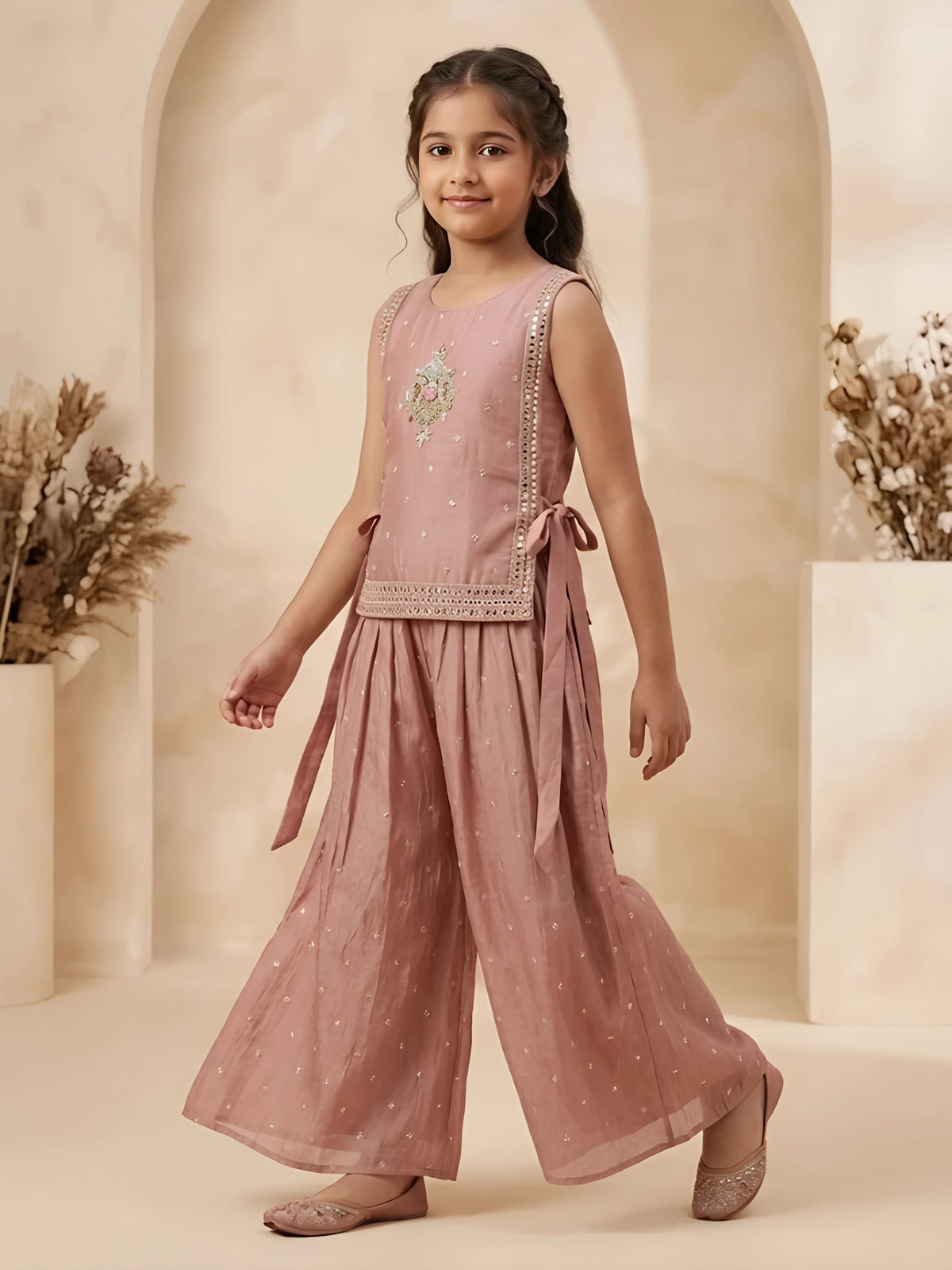 Girls peach sleeveless embroidered tunic top with side tie-ups paired with matching wide-leg flared palazzo pants.