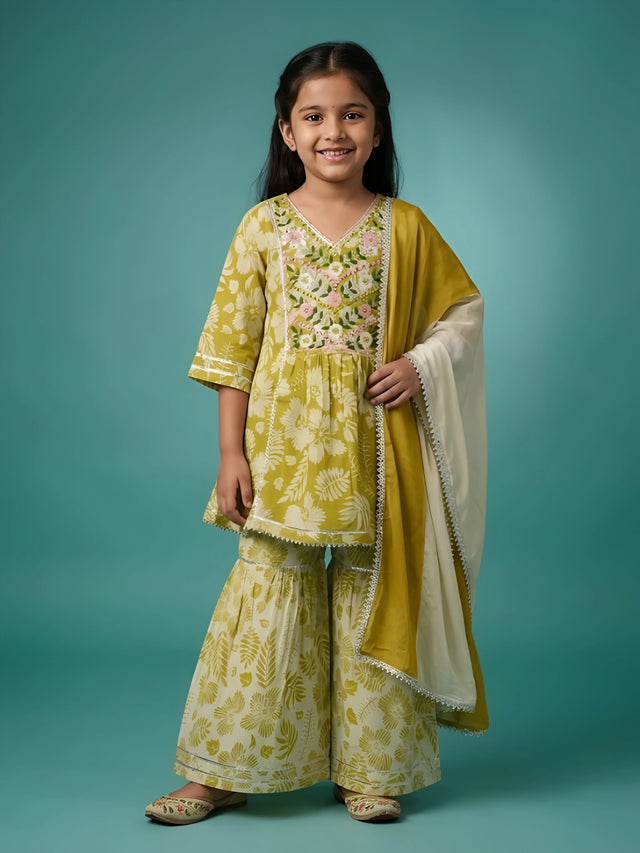Young girl wearing an olive green floral printed sharara suit with embroidered V-neckline and matching dupatta