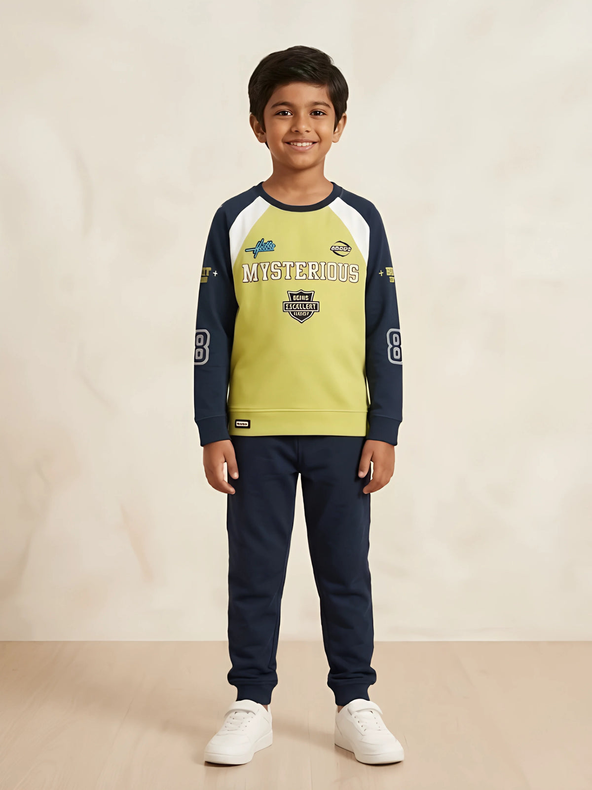 Young boy wearing a green and navy blue full sleeve graphic t-shirt with navy joggers and white sneakers