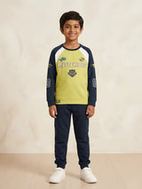 Young boy wearing a green and navy blue full sleeve graphic t-shirt with navy joggers and white sneakers