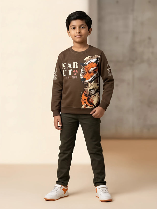 Young boy wearing a brown full sleeve Naruto graphic printed casual t-shirt with dark green pants and white sneakers
