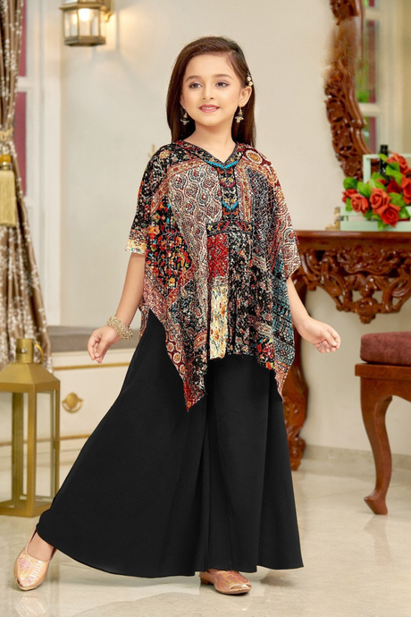 Young girl wearing a short-sleeved, knee-length black party dress with large puff sleeves and a prominent gold 3D rose flower on the chest.