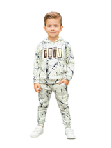 Full-length image of a young boy wearing a cream and black marble-printed hoodie and matching jogger pants coordinate set with a "GOOD" graphic on the chest, paired with white sneakers.