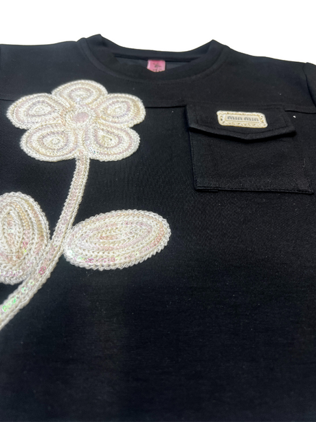 Girls' long-sleeved black top with a large, sparkly flower appliqué made of rhinestones or pearls on the chest.

Export to Sheets