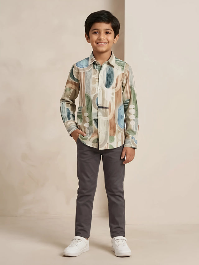 Young boy wearing a long-sleeve green abstract printed casual shirt paired with dark trousers