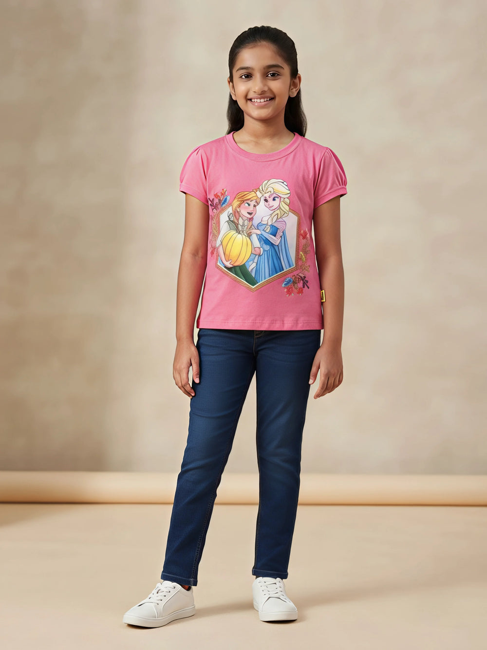 Young girl wearing a pink Disney Frozen printed t-shirt with puff short sleeves paired with blue jeans