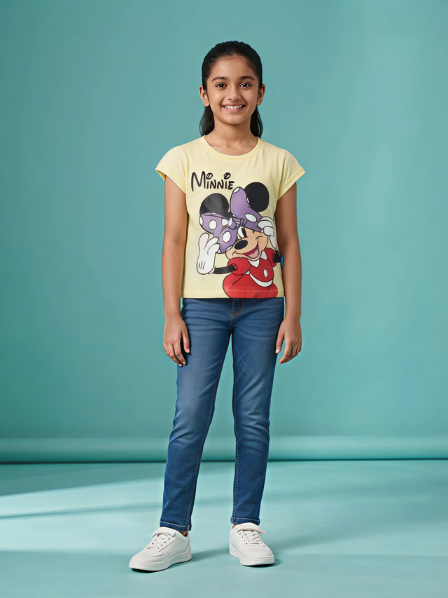 Young girl wearing a light yellow Minnie Mouse graphic printed round-neck t-shirt with blue denim jeans