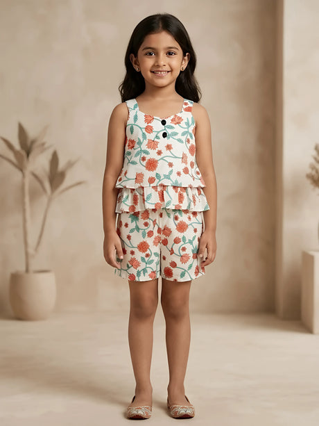 Young girl wearing a cream co-ord set with peach and teal floral prints, featuring a ruffled sleeveless top and matching shorts