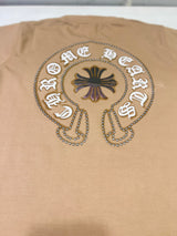 Tan/Brown boys' short-sleeve T-shirt with a small circular distressed cross and text logo graphic on the left chest, hanging on a white background.