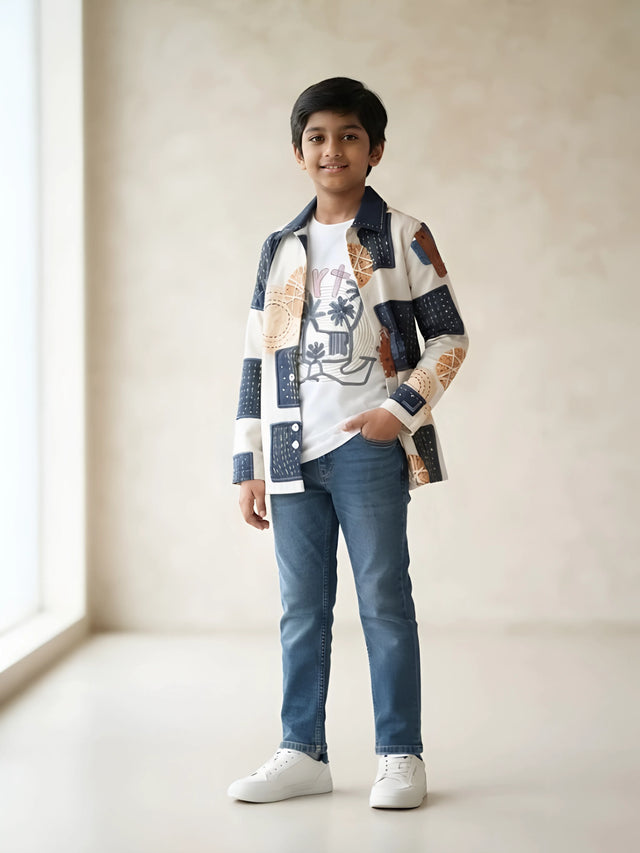Boy wearing a cream full sleeve printed casual shirt over a white graphic t-shirt and blue jeans