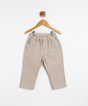 Boys' plain khaki/cream casual pants with an elastic waist, front pockets, and a straight leg fit, hanging on a wooden hanger.