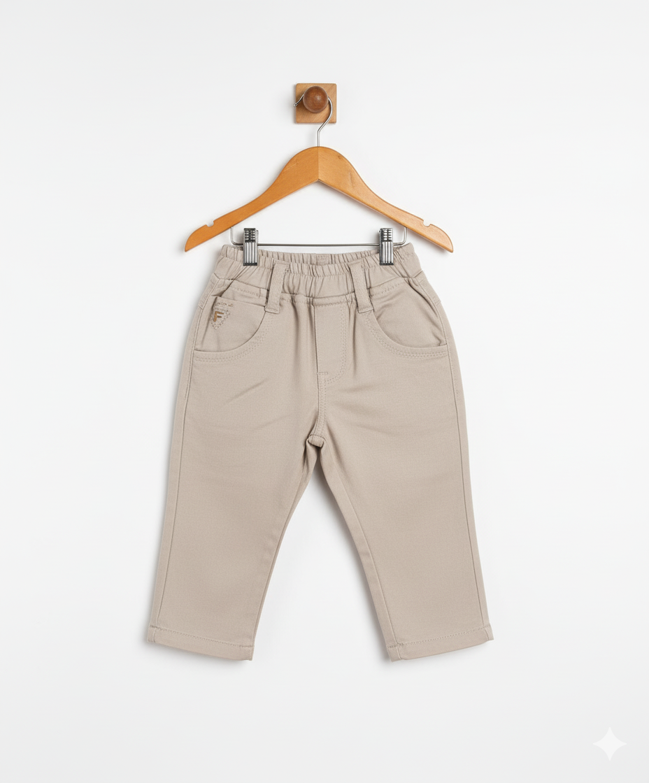 Boys' plain khaki/cream casual pants with an elastic waist, front pockets, and a straight leg fit, hanging on a wooden hanger.