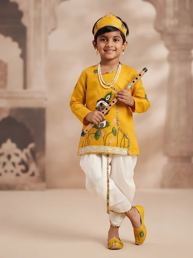 Little boy wearing a yellow printed angrakha kurta with white dhoti and matching yellow headband for Kanha look
