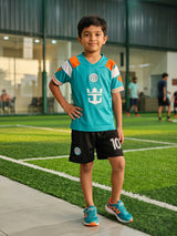 A young boy posing on a football turf field wearing a teal green and orange athletic jersey with matching black sports shorts printed with number 10.