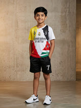 Young boy smiling while wearing a multi-color football-inspired t-shirt with red, yellow, and white panels and matching black sports shorts with a number 7 print.