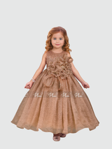Young girl smiling in a full-length, voluminous rose gold/bronze shimmering party gown. The dress features a large, ruffled 3D flower appliqué on the bodice and a small matching bow at the waist