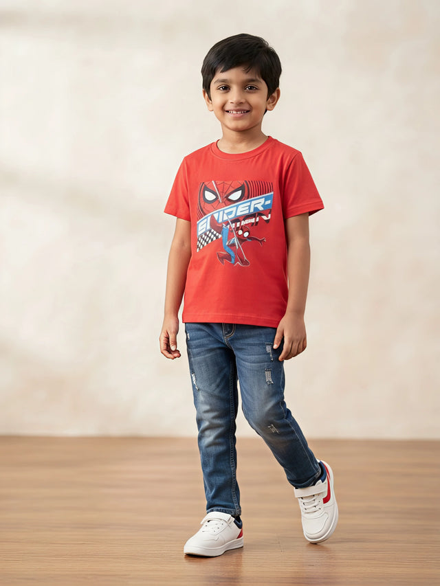 Young boy wearing a red short-sleeve Spider-Man graphic print t-shirt paired with blue jeans.