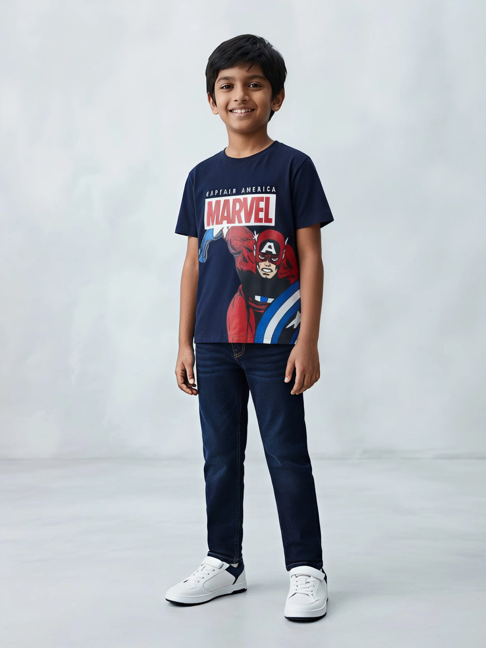 Young boy wearing a navy blue Marvel Captain America graphic printed t-shirt and blue jeans.