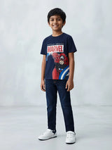 Young boy wearing a navy blue Marvel Captain America graphic printed t-shirt and blue jeans.