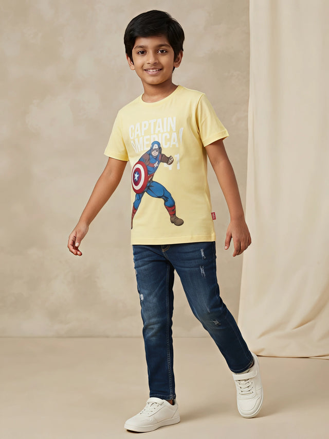 Young boy wearing a bright yellow round-neck t-shirt featuring a Captain America graphic print paired with blue jeans.