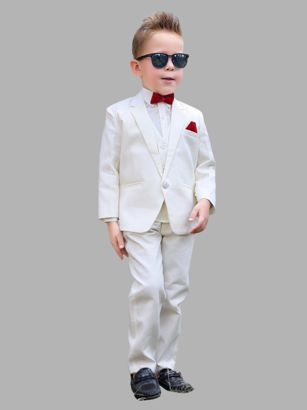 Full-length image of a young boy wearing a three-piece white/cream formal suit with a red bow tie and pocket square, along with sunglasses and black shoes.