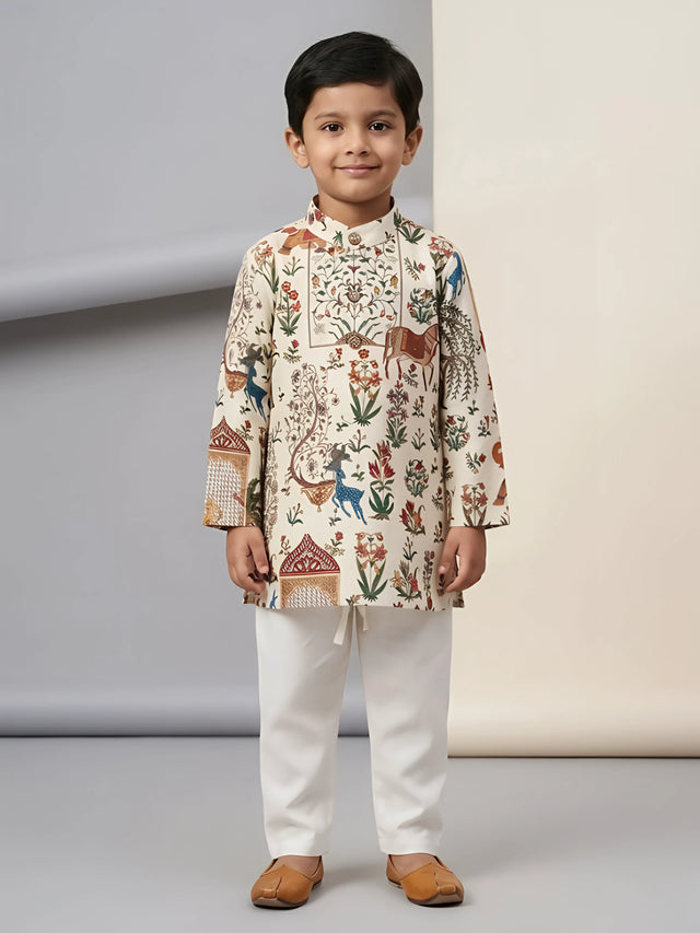 Young boy wearing cream floral and animal printed kurta with off-white pyjama trousers and tan juttis