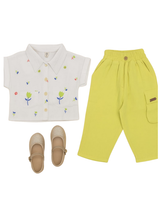 Girls' two-piece set featuring a white short-sleeve collared shirt with colorful floral embroidery, paired with bright neon lime green cargo pants with an elastic waist, and gold glitter Mary Jane shoes.