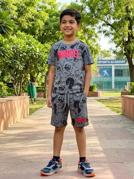 A young boy wearing a stylish grey Marvel print co-ord set consisting of a graphic t-shirt and matching shorts with a drawstring waist.