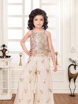 Young girl wearing a beautiful cream three-piece lehenga set with a flared skirt, sleeveless crop top, and embroidered open jacket, all featuring colorful pastel floral embroidery.