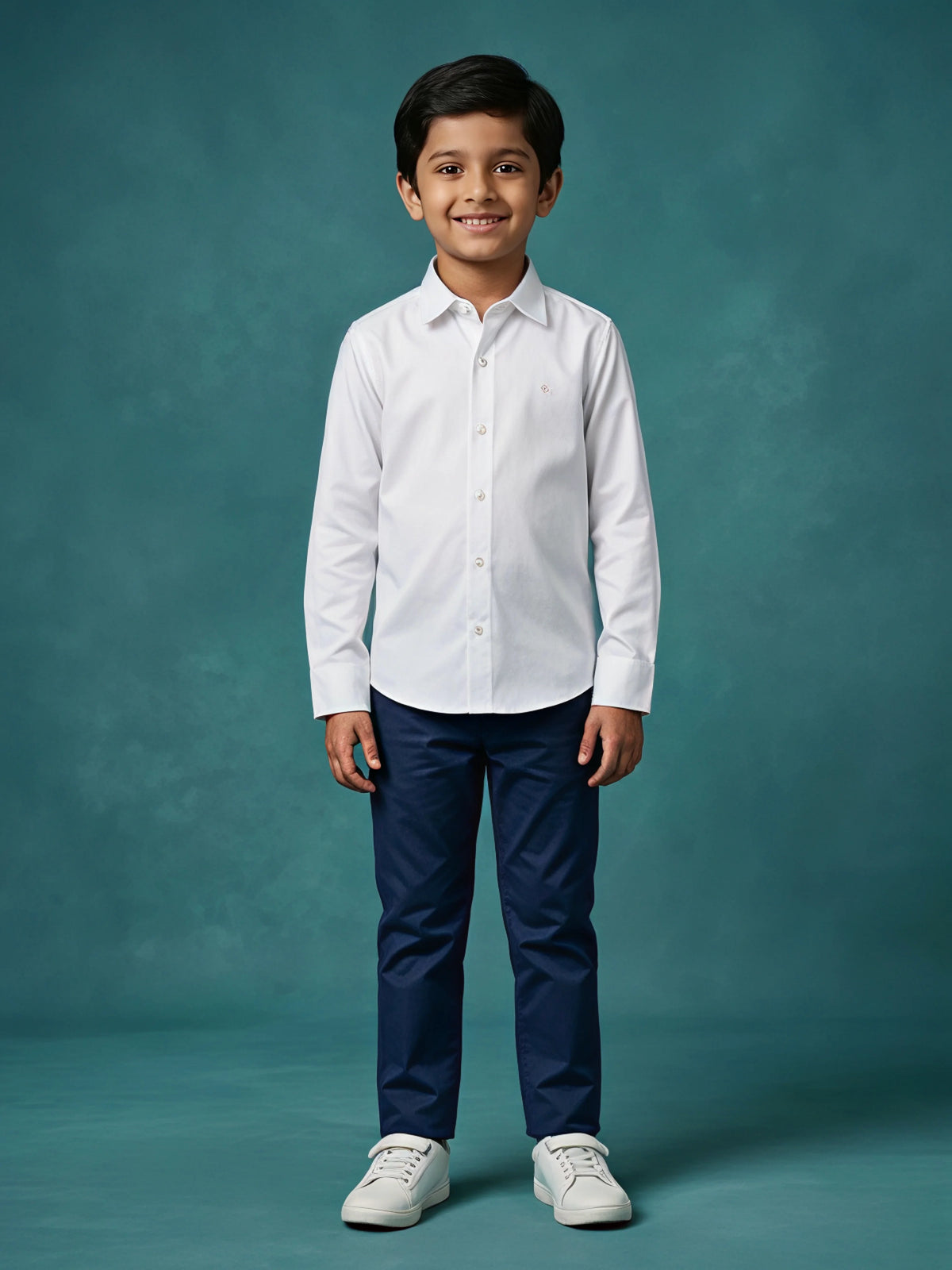 Young boy wearing a crisp white long sleeve casual shirt paired with navy blue trousers