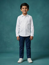 Young boy wearing a crisp white long sleeve casual shirt paired with navy blue trousers