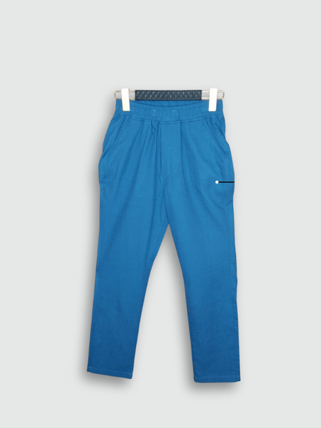Boys' plain, bright blue casual pants made of a lightweight knit fabric, showing the elastic waist and slanted side pockets, hanging on a hanger.