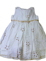 White girls' sleeveless dress with beige floral cutwork embroidery and a thin champagne-colored satin ribbon belt/sash.

Export to Sheets
