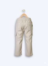 Boys' cream/light beige cargo pants with an elastic waist, green drawstring, and large flap cargo pockets.
